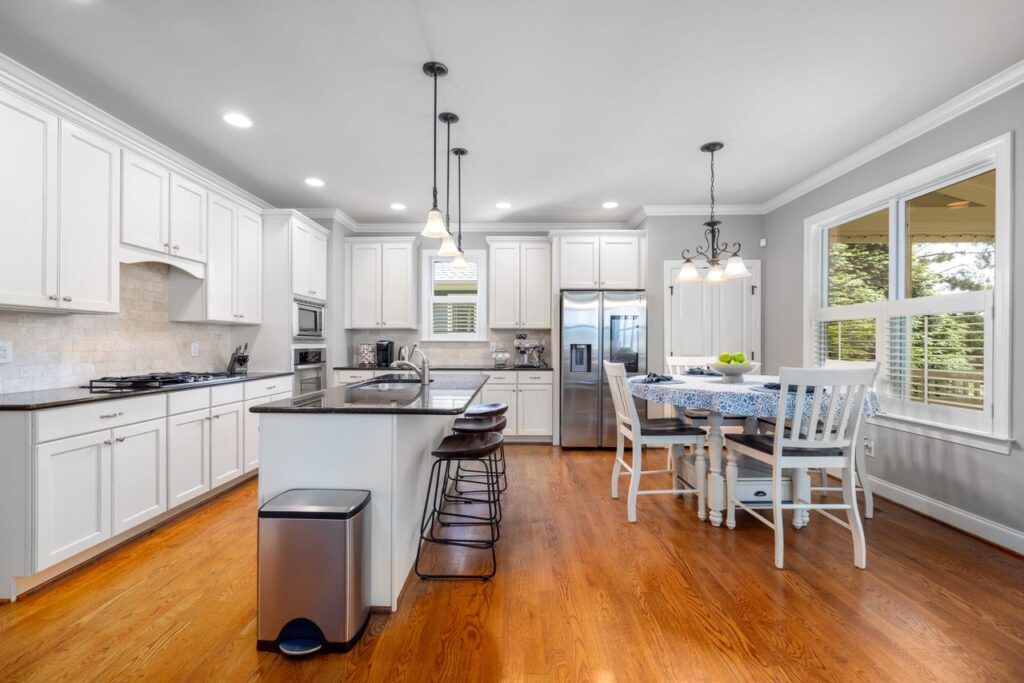 Bright and spacious modern kitchen with white cabinets and wooden flooring.
